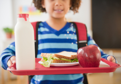 African American school girl holding lunch on a tray